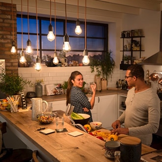 Couple talking underneath Philips vintage LED bulbs hanging from the ceiling creating a cozy warm glow