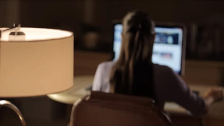 Woman working at home with a desk lamp in the foreground