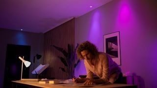 Philips Hue smart LED lights create vibrant purple and pink ambiance in living room, showcasing customisable mood lighting for movie nights and relaxation in modern homes.