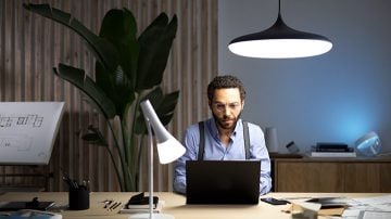 A man working at home under a smart luminaire