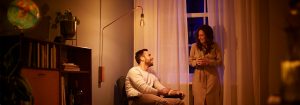 "Vintage-style LED bulb floor lamp creating warm ambiance for couple's evening conversation, showcasing energy-efficient mood lighting in cosy living room."