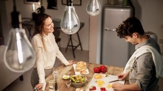 "Modern kitchen with vintage style LED pendant lights illuminating two women enjoying dinner, creating warm, inviting atmosphere."